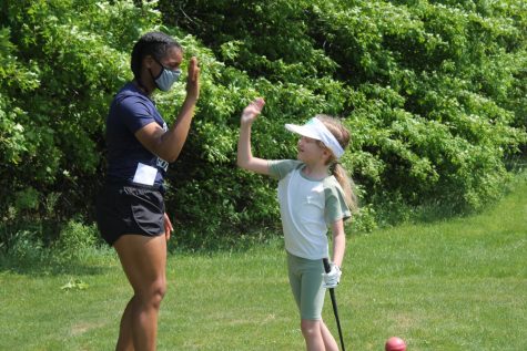 Junior Courtney Morgan gives one of the youth golfers a high five May 23 during the last session of the program. (photo by Abigail Myers)