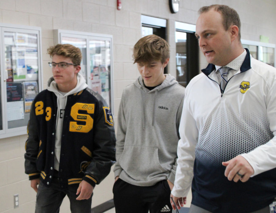 Junior Donovan Paes and freshman Cohen Klimak start their clap outwalk with Principal Brett McCann for the schoolwide sendoff for states Thursday afternoon.