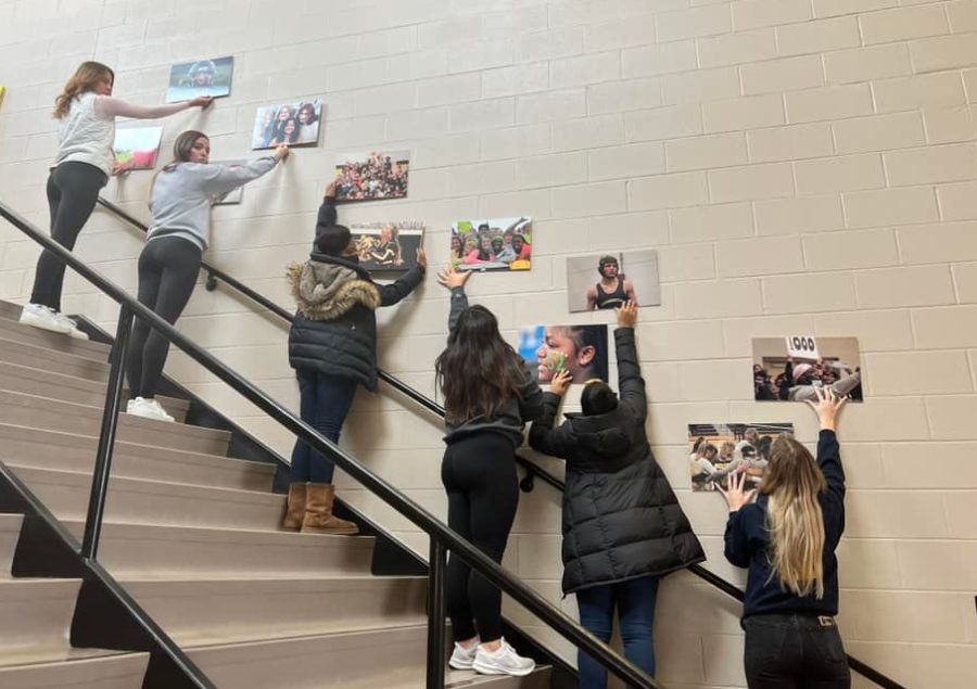 Yearbook seniors hold up the photos for adviser Polly Dierkens and other staff members to decide where they should be hung. They decided against the main stairwell because they did not cover enough of the wall to make an impact.