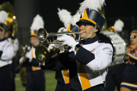 Junior trumpet player Tyler Paul marches on the football field.